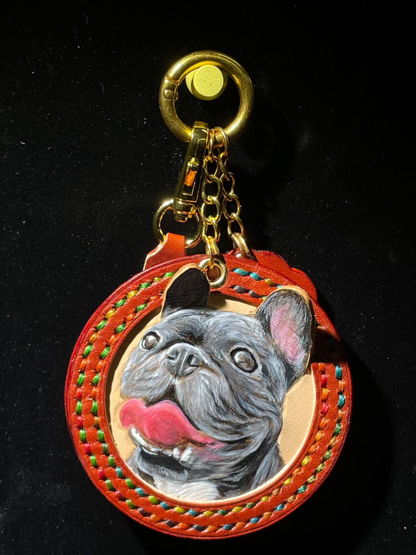 Supplier photograph of a black dog portrait on a round charm with rainbow stitching.