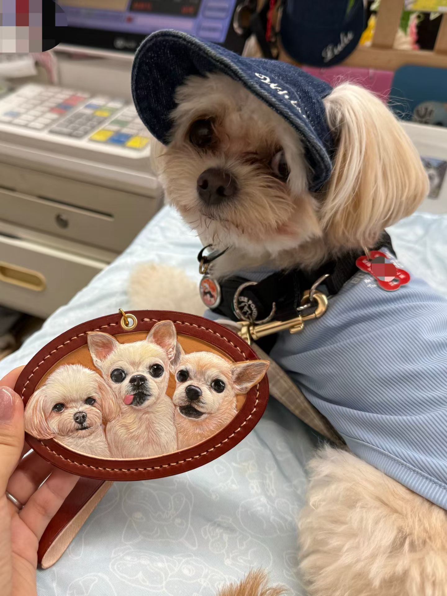 Supplier photograph of a three-dog oval leather charm beside a small dog.